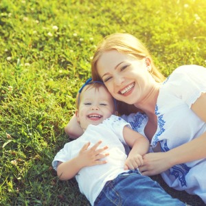 Mom and toddler laying in grass smiling