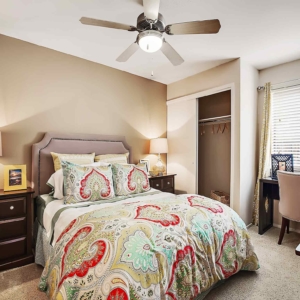 Second bedroom of Galleria model home with modern furniture, open closet and desk/sitting area